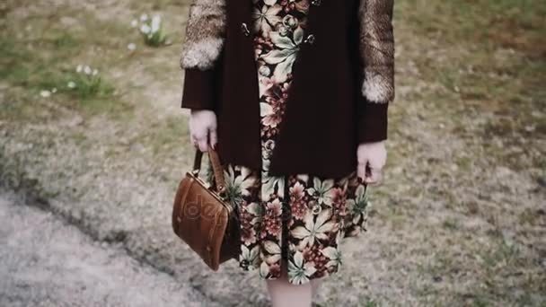 Sint-Petersburg, Rusland - 9 mei 2017: Mooie jonge vrouw in vintage bloemen jurk en bontjas poseren in het city park — Stockvideo