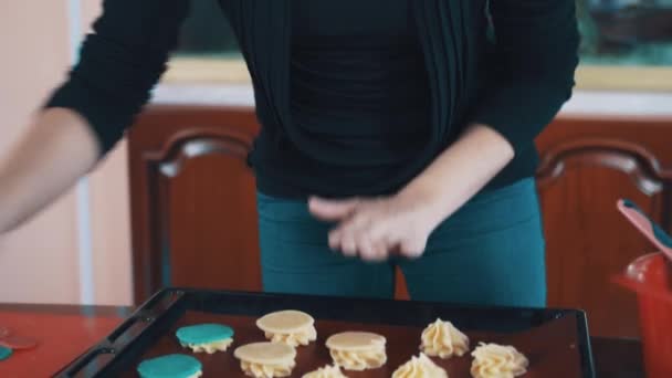 Mujer confitera pone círculos de masa beige en pilas de crema en la bandeja para hornear — Vídeo de stock