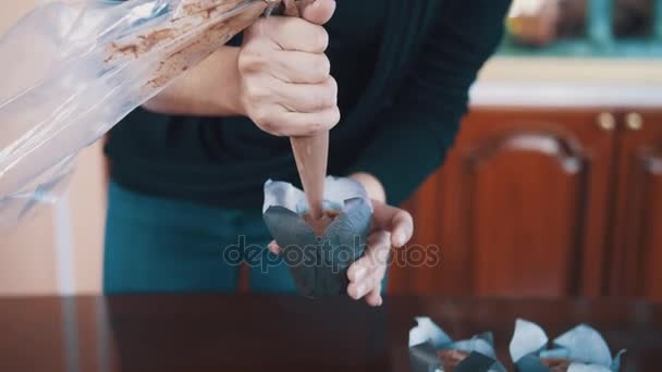 Pastelería-cocinero manos de mujer aprieta relleno de chocolate en magdalenas en la mesa — Vídeos de Stock