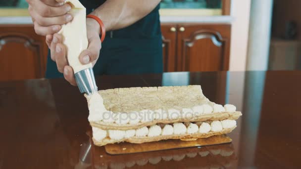 Pasta katının üzerine doğrultusunda whiped krem puffs pasta aşçı kaslı adam sıkıyor — Stok video
