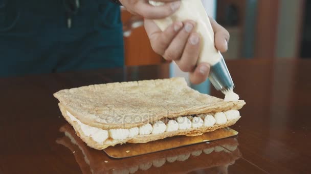 Cukiernik wypolerowany człowiek ściska whiped Creme kłęby w linii na warstwę ciasta — Wideo stockowe