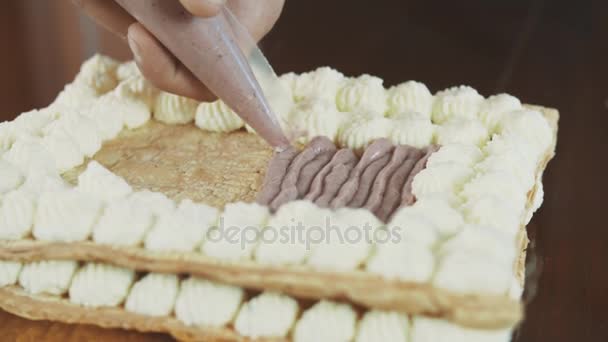 Baker hombre manos aprieta relleno crema fuera de la manga en la capa de pastel — Vídeo de stock