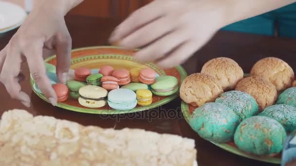 Woman pastry cook hands places colorful macarons on plate upon table — Stock Video