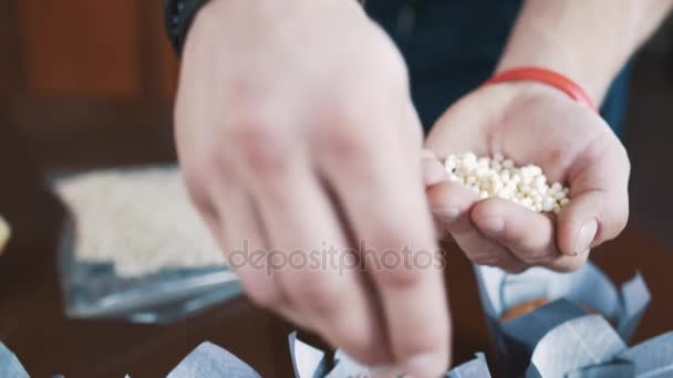 Кондитерські чоловічі руки прикрашають манну крупу рисовими кульками — стокове відео