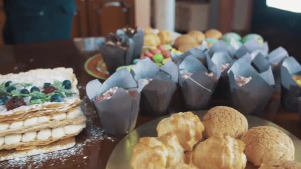 Banketbakkers paar staande boven tafel met desserts op keuken — Stockvideo