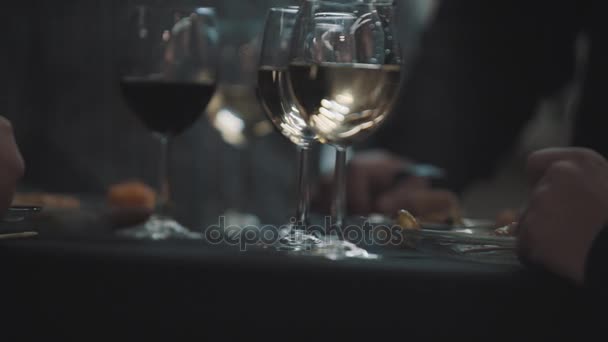 Copos de vinho na mesa do banquete, homens de ternos comendo carne em espetos — Vídeo de Stock