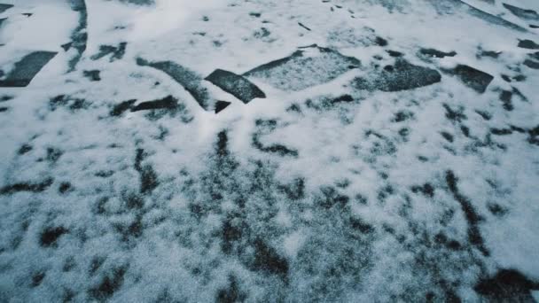 Bevroren rivier verbrijzelde ijs oppervlak bedekt met sneeuw, ruïneerde Voortbouwend op oever — Stockvideo