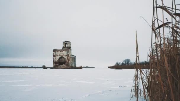 Покинута церковна будівля посеред замерзлого озера, вкритого снігом — стокове відео