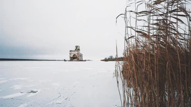 Förstörda kyrkan byggnad i mitten av frusen sjö täckt av snö — Stockvideo