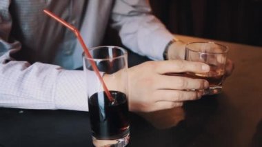 Erkek ekose gömlekli bardak viski tablo üzerine café'de tutan eller