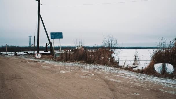 Landsvägen som leder till bron i mitten av frusna floden täckt av snö — Stockvideo