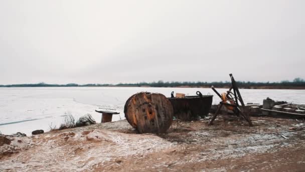 Bevroren meer oever, brug en verroeste pier met boot — Stockvideo