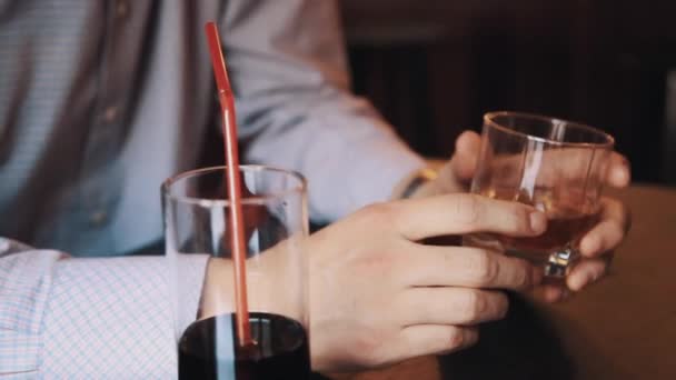 Мужские руки в клетчатой рубашке держа стакан виски на столе в баре — стоковое видео