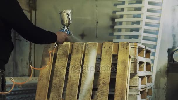 Працівник використовує аспіратор для фарбування дерев'яного піддону білого кольору в майстерні — стокове відео