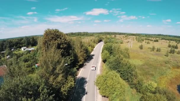 Tiro aéreo de estilo antigo carro branco montando na floresta hightway calha — Vídeo de Stock
