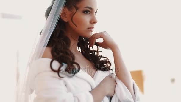 Young bride in white robe and vail standing on balcony waiting for fiance — Stock Video