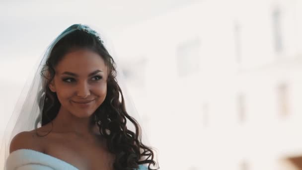 Молода наречена в білому халаті і схованці посміхається на балконі в день весілля — стокове відео