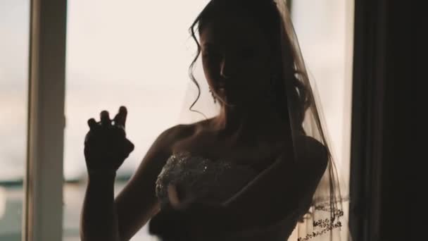 Young bride in wedding dress sprinkles parfume in front of window — Stock Video