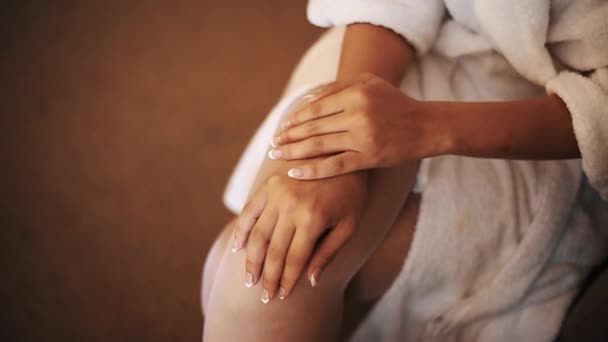 Femme en peignoir met la main sur les jambes croisées en collants blancs — Video