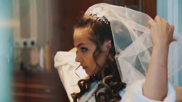 Giovane bella sposa ragazza si mette il velo bianco davanti allo specchio — Video Stock