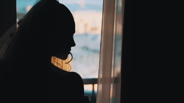 Silhouet van bruid meisje te wachten voor de bruidegom voor raam — Stockvideo