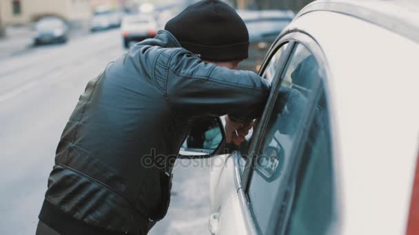 Hombre de chaqueta negra y sombrero de gorro se apoya en la ventana del coche en la ciudad — Vídeos de Stock