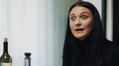 Genç esmer kadın konuşmak ve İçecek şarap cam yemek masasında