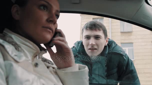 Божевільний молодий чоловік дивиться на жінку, що говорить на мобільний телефон — стокове відео