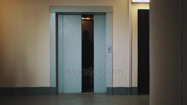 Man walking out elevator with suitcase in dormitory house corridor — Stock Video