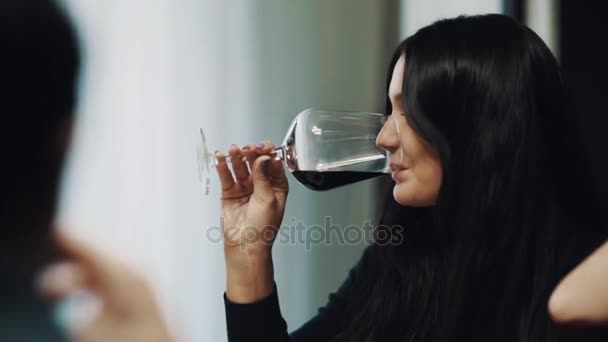 Jonge brunette vrouw lachend en drinken wijn uit glas op tafel — Stockvideo