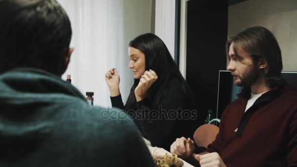 Hombre y mujer pareja mastica mientras habla con amigo en la mesa de la cena — Vídeo de stock