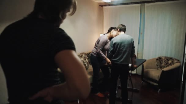 Мужчина играет шутки друзья пара, направляя пистолет на них в гостиной — стоковое видео