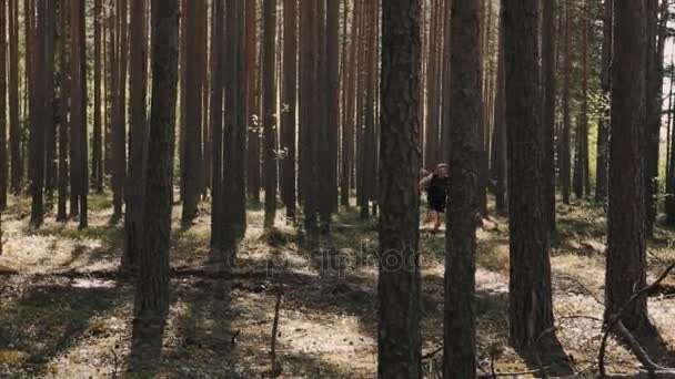 嬉戏的年轻男子，贯穿常绿乔木林 — 图库视频影像