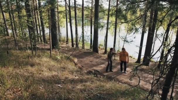 Двое друзей гуляют по лесной тропинке и начинают спорить в солнечный день. — стоковое видео