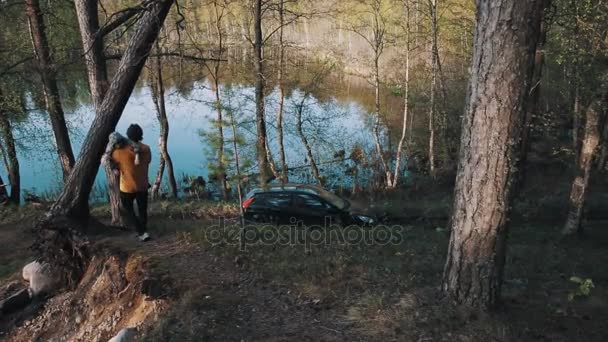Father brings little son trough forest to parked car near lake — Stock Video