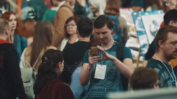 SAN PETERSBURG, RUSIA - 20 DE MAYO DE 2017: Un hombre con un teléfono inteligente toma fotos en la multitud de personas en el festival — Vídeo de stock