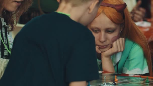 SAN PETERSBURG, RUSIA - 20 DE MAYO DE 2017: Chica con peluca de jengibre con cuernos de diablo y corazones en las mejillas jugando al juego de mesa — Vídeos de Stock