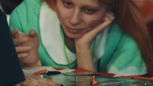 СЕНТ-ПЕТЕРБУРГ, РОССИЯ - 20 МАЯ 2017 года: Девушка в рыжем парике с демоническими рогами и сердцами на щеках играет в настольную игру — стоковое видео