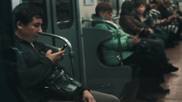Санкт-Петербург, Російська Федерація - 30 вересня 2016 року: Середній у віці людина за допомогою яскраві жовті смартфон сидить у переміщенні метро тренува — стокове відео