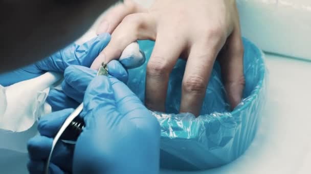 Красавчик в салоне использует щипцы для ногтей, чтобы отрезать кутикулу с пальцев клиента — стоковое видео