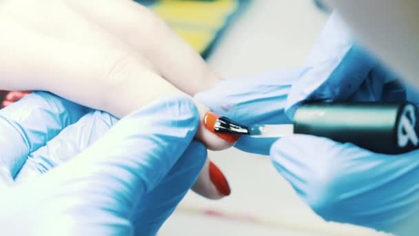 Manicurista mano pone esmalte de uñas rojo en el cliente uñas del pulgar en salón de belleza — Vídeo de stock