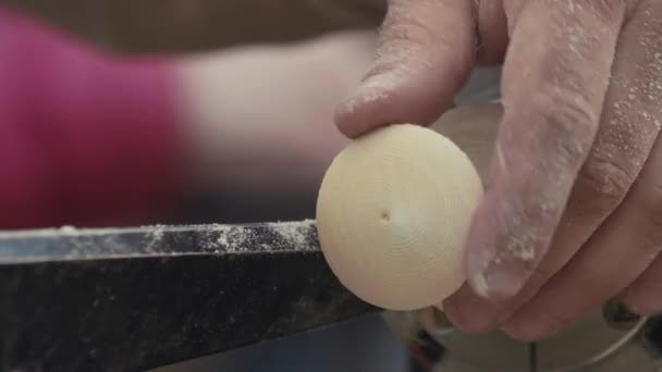 Руки деревообработчика вырезают дверную ручку из деревянной детали крутящейся на машине — стоковое видео