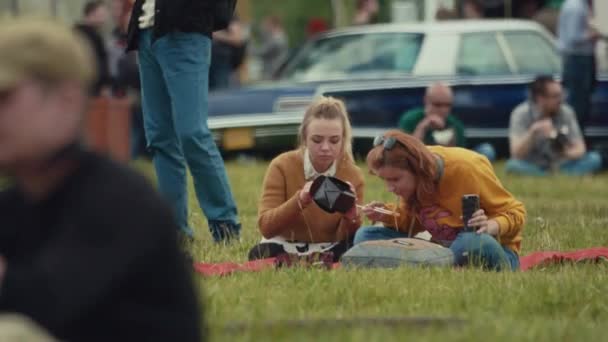 Sankt Petersburg, Ryssland - 24 juni 2017: Två unga kvinnor sitter på gräset äta nudlar ut rutan på sommarfestival — Stockvideo