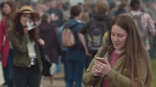 SAINT PETERSBURG, RÚSSIA - JUNHO 24, 2017: Jovem mensagem de texto no telefone inteligente no festival de verão lotado — Vídeo de Stock