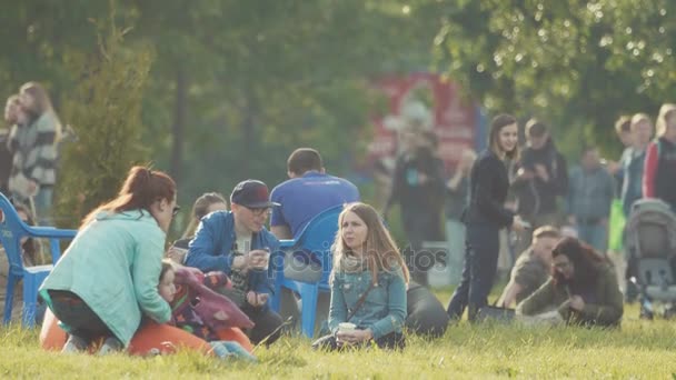SAINT PETERSBURG, RÚSSIA - JUNHO 24, 2017: Jovem família sentada na grama, conversando no festival de verão ao ar livre — Vídeo de Stock