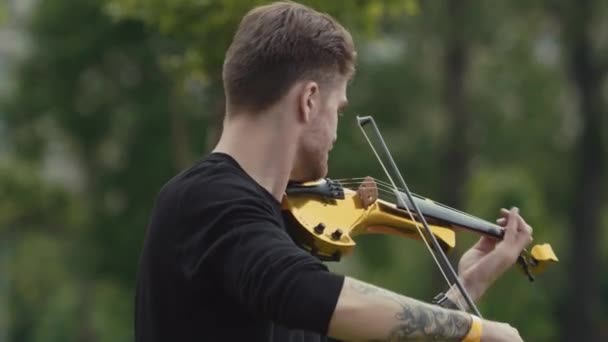 Sankt Petersburg, Ryssland - 24 juni 2017: Unga stiliga musiker man spelar elektrisk fiol i stadsparken — Stockvideo