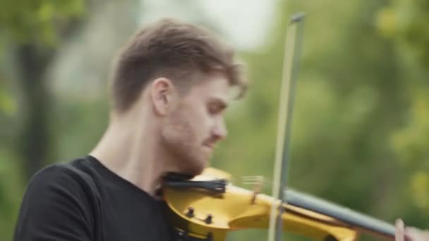 SAN PETERSBURG, RUSIA - 24 de junio de 2017: Joven músico alegre tocando el violín eléctrico en el parque de la ciudad — Vídeos de Stock