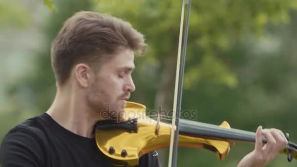Saint Petersburg, Federacja Rosyjska - 24 czerwca 2017: Człowiek młody muzyk radosny w skrzypce elektryczne w parku miejskim — Wideo stockowe