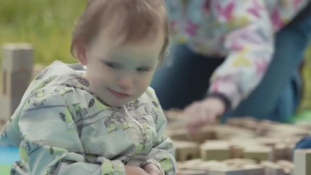 St. petersburg, russland - 24. juni 2017: kleinkind steckt marmorkugel in holzklotz und spielt im stadtpark — Stockvideo