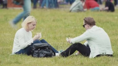 Saint Petersburg, Rusya - 24 Haziran 2017: kalabalık yaz şehir Festivali Park hamburger yeme çimenlerin üzerinde oturan Çift